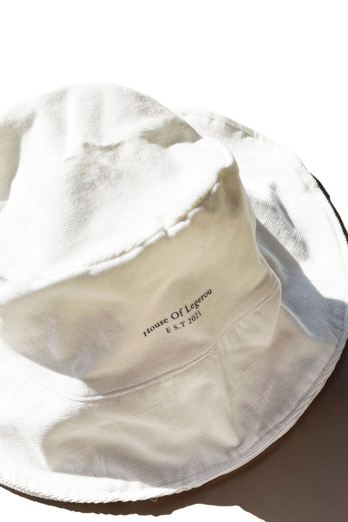 White Corduroy bucket hat featuring 'House of Legerou' painting in Black.